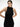 A female model standing in a black ribbed halter-neck dress in a minimalist white space.