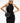 A female model wearing a sleek black round yvy crossbody bag with an adjustable strap over a black sleeveless dress. The bag features a minimalist design and a horizontal leather band detail