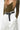 a closeup of a woman wearing a wide black yvy belt with silver eyelets with white pants and olive longsleeve shirt